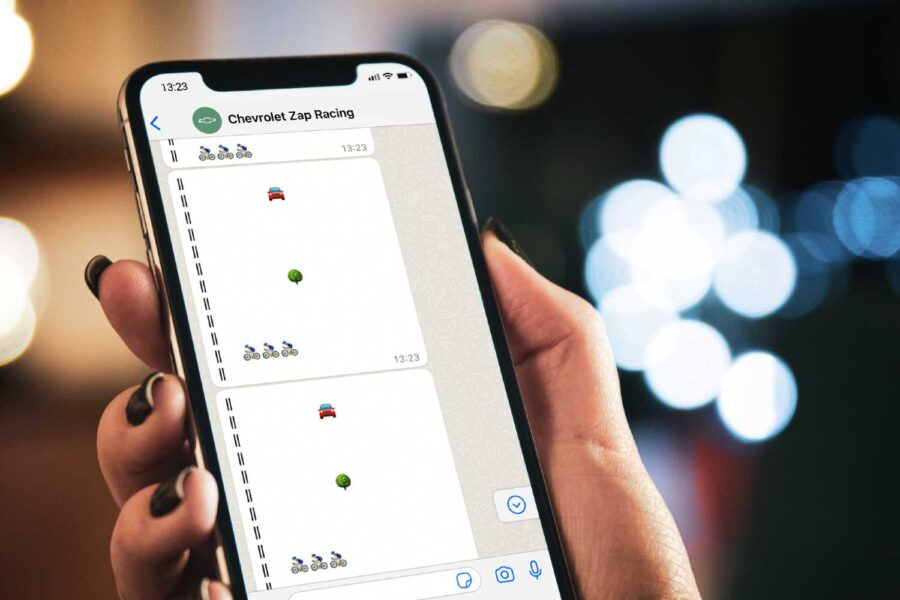 Mão segurando celular com o jogo Chevrolet Zap Racing rodando no WhatsApp